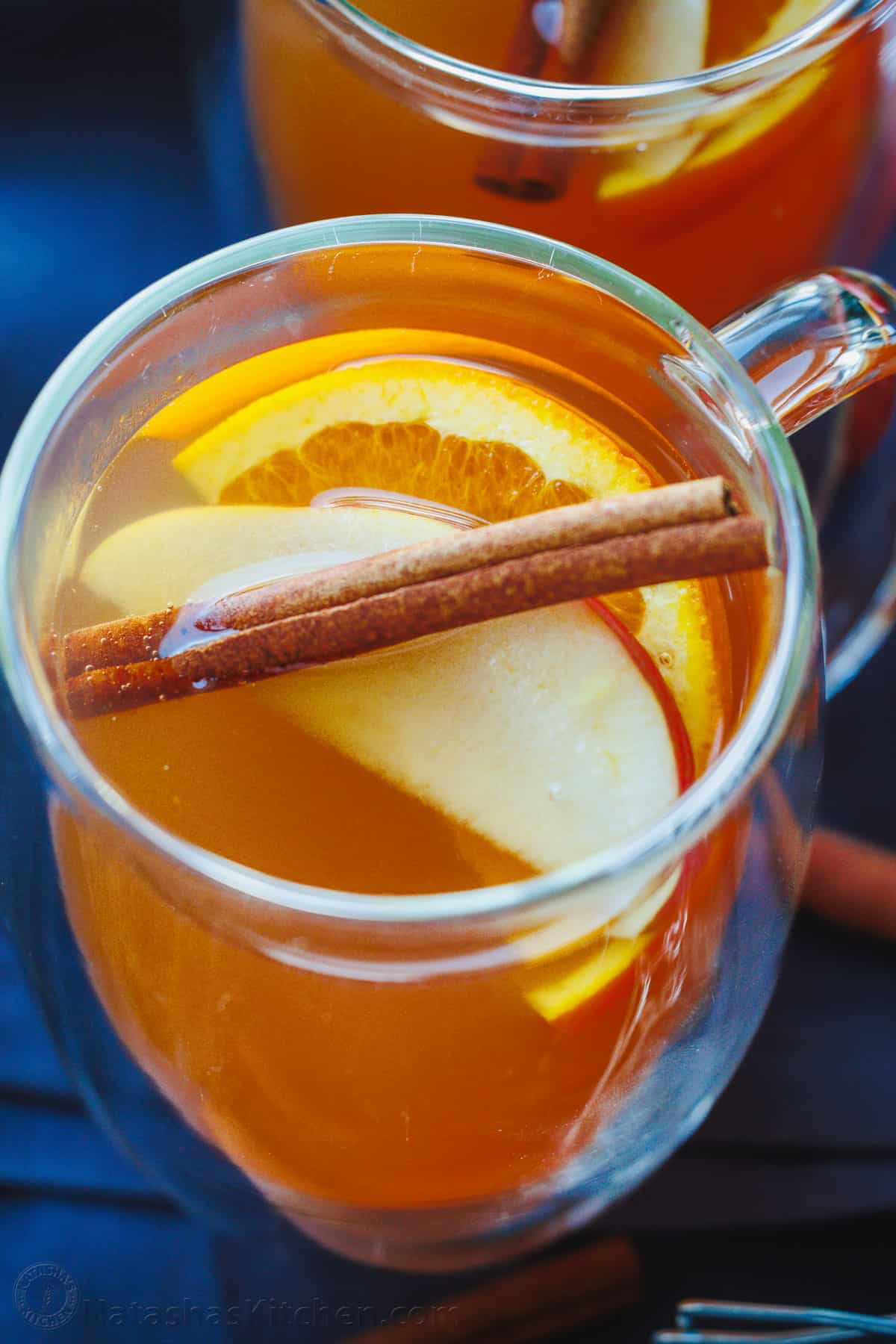 Apple cider with cinnamon stick and apple and orange slices in a mug