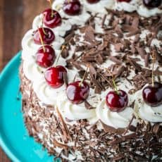 Black Forest Cake (a famous German Chocolate Cake) with 4 chocolatey layers, 1 lb of kirsch infused cherries and whipped cream. So good!! | NatashasKitchen.com