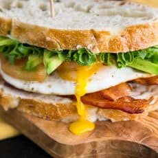 A close up of a breakfast BLT sandwich on a cutting board