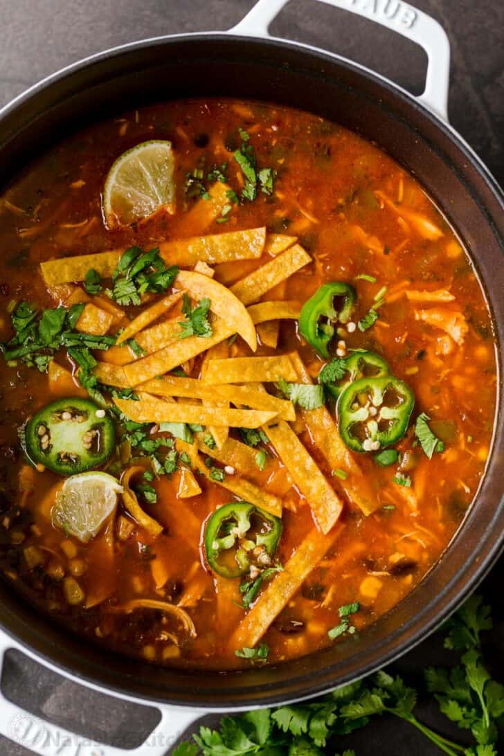 Easy chicken tortilla soup in pot garnished with tortilla strips, jalapeños and cilantro