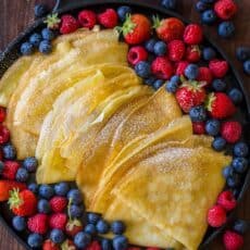 Crepes arranged on a skillet and dusted with powdered sugar