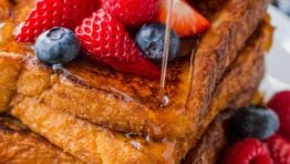 French toast slices stacked and served with berries and maple syrup