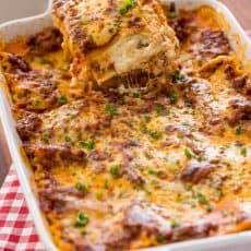 Piece of lasagna being lifted from baking dish
