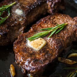 Pan-Seared Steak on skillet topped with butter and fresh rosemary