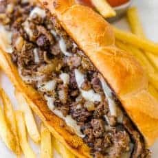 Philly cheesesteak served on hoagie roll with fries and ketchup