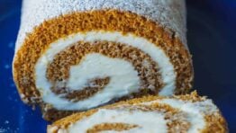 Pumpkin Roll Cake with powdered sugar and a slice