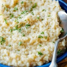 Risotto in blue bowl garnished with parmesan and parsley