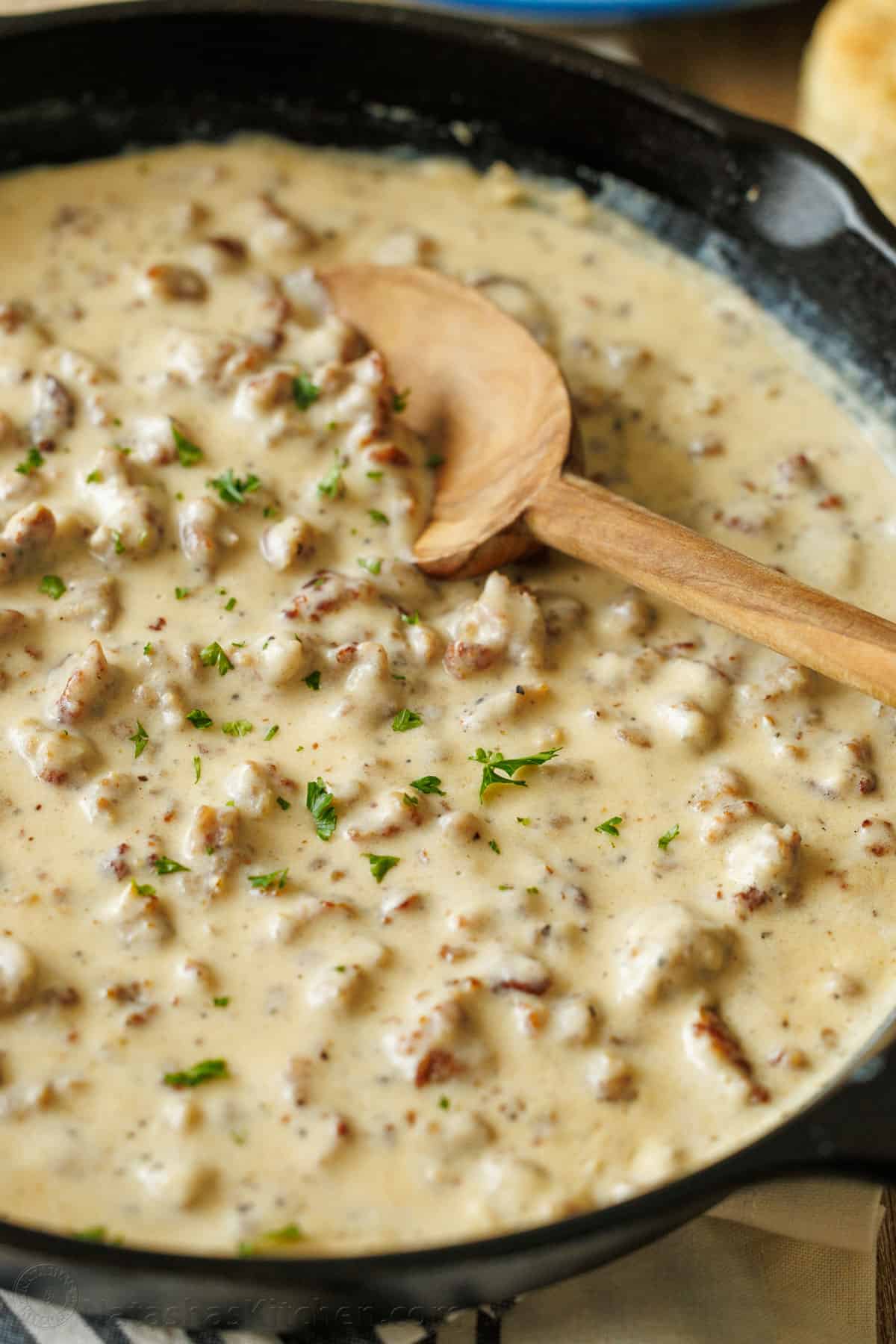 Souther white sauce with pork crumbles in a pan with a wooden spoon