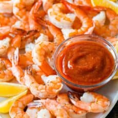 Shrimp cocktail with baked shrimp and homemade shrimp cocktail sauce on platter with lemon wedges