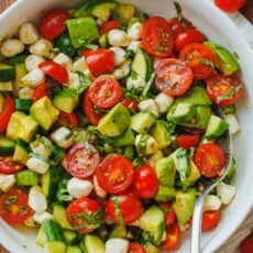 tomato cucumber mozzarella salad in a bowl with a spoon